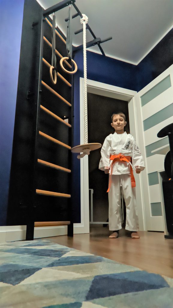 dziecko trenuje karate przy drabince gimnastycznej